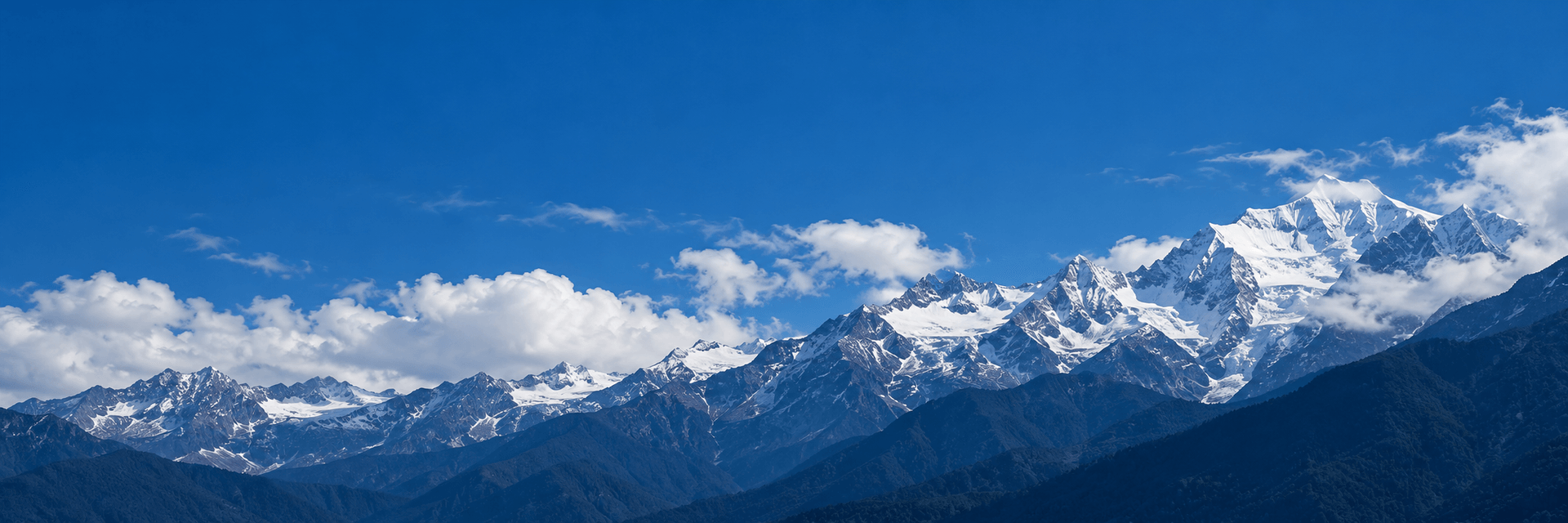 蓝天白云下的雪山与深色山坡